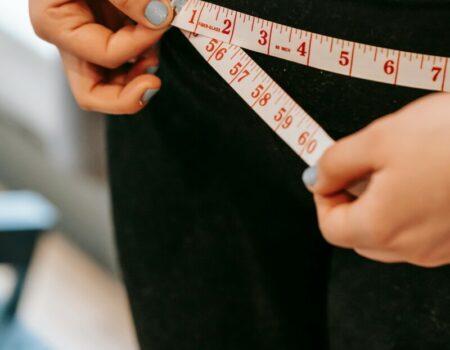 person putting measuring tape round their waist