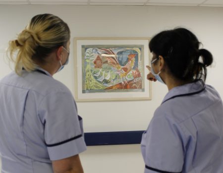 two members of staff looking at a painting
