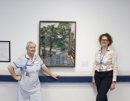 Two members of staff standing next to art work
