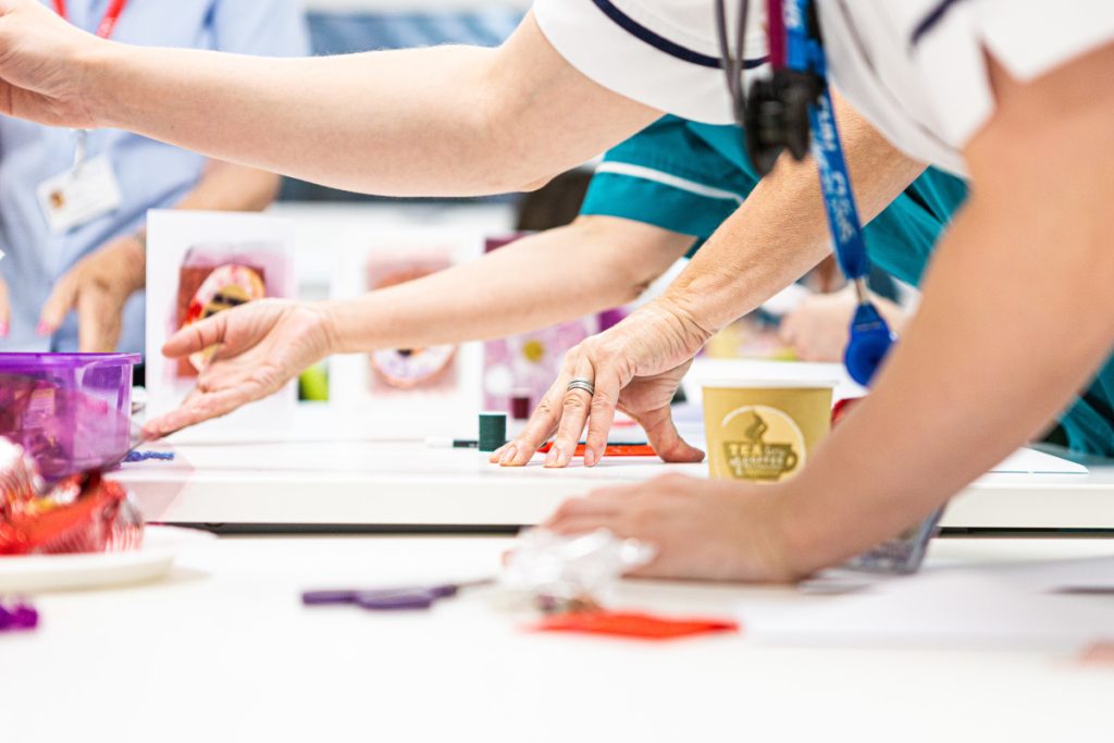 Members of staff creating artwork with hands on table