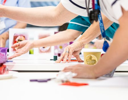 Members of staff creating artwork with hands on table