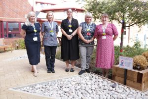 Maternity staff stand beside a baby loss remembrance feature of the Cherry Tree Garden