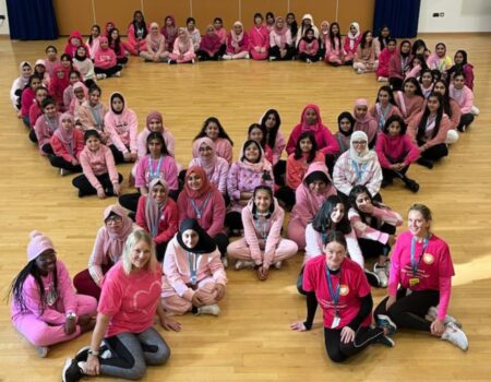 Students wearing pink and sitting in a ribbon shape