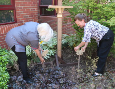 Staff installing wooden butterflies next to the bird table