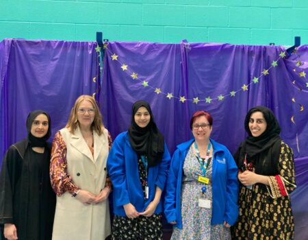 School and charity staff in front of a blue background with a stars garland