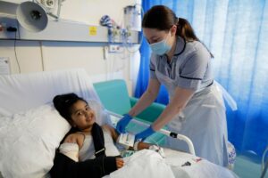 A child in a sling having her blood pressure taken by a nurse