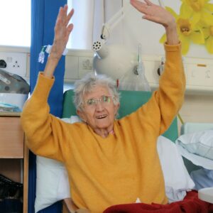 A patient smiling and waving her hands in the air