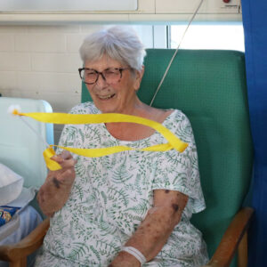 A patient smiling and twirling a ribbon