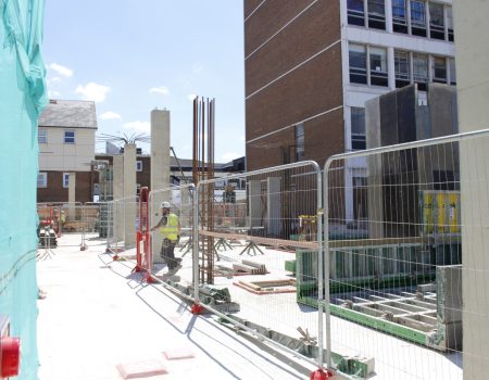 Man standing next to fencing on redevelopment groundwork