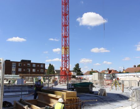 Tower crane on the redevelopment site with workers in foreground
