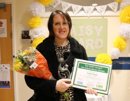 Helen Braid smiling at the camera holding certificate and flowers