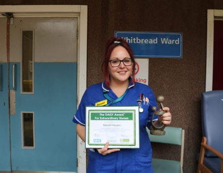 Naomi smiling with award and certificate