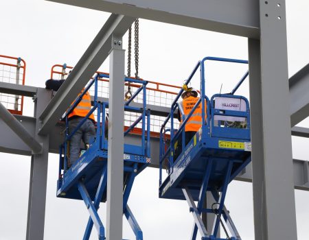 Two workers is high vis jackets fixing the final beam in