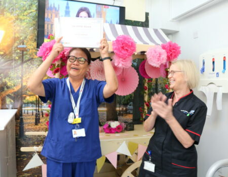 Ali lifting the certificate above her head while Bill claps her