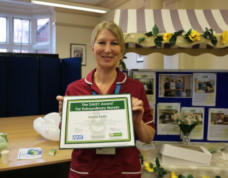 Laura holding her DAISY certificate