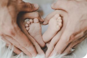 Baby feet surrounding by parents hands to make a heart