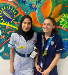Two Paediatric staff smiling in front of artwork