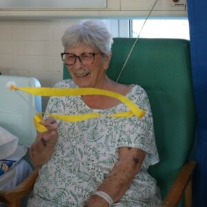 A patient smiling and twirling a ribbon