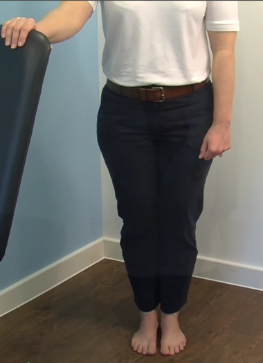 Person standing with their feet together, holding onto a stable support
