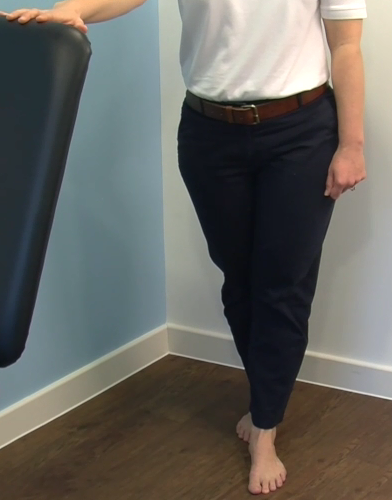 Person standing with their feet together, with one heel lifted from holding onto a stable support